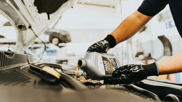 Mechanic pouring transmission fluid into car engine, automotive maintenance close-up