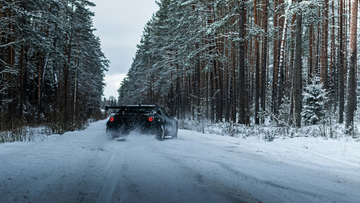 Sports car driving on a snowy forest road, winter automotive scene