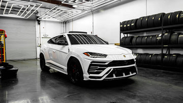 White luxury SUV in auto workshop with tire racks and modern LED lighting