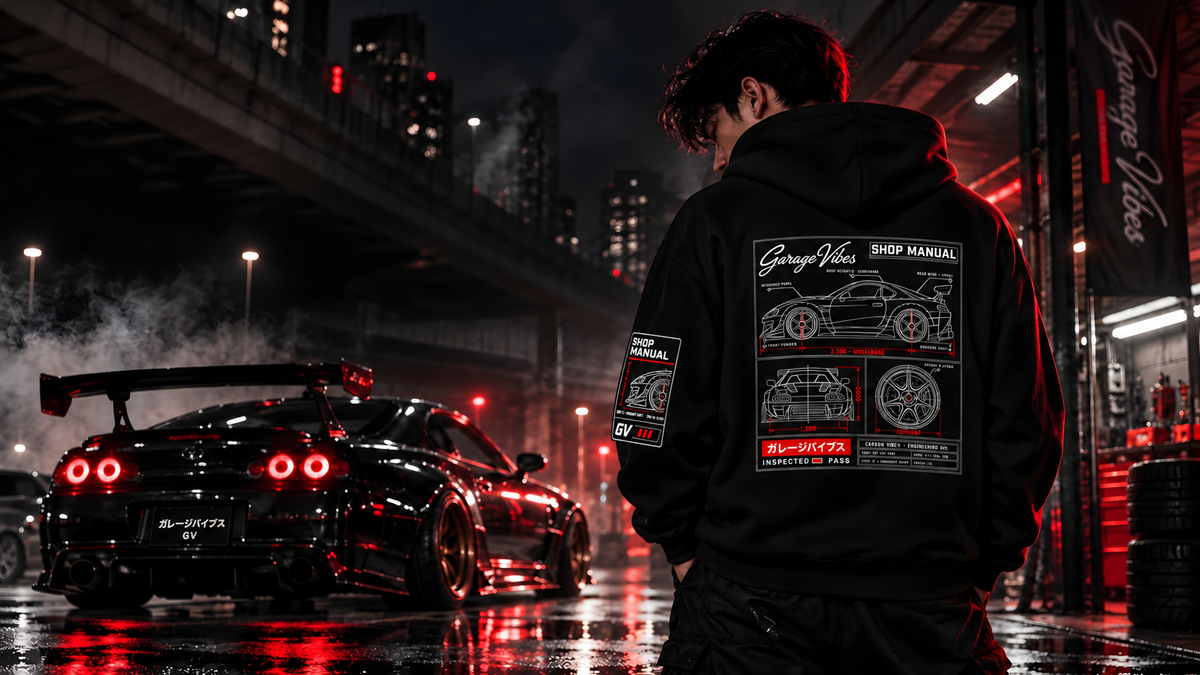 Back of a black Garage Vibes Shop Manual hoodie on a rainy city street at night