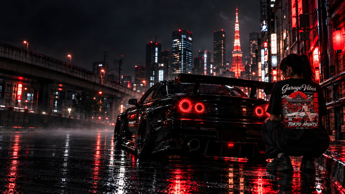 Back view of a woman crouching beside a black JDM sports car on a rain-soaked Tokyo street at night, wearing a black Garage Vibes "Tokyo Nights" graphic tee. Red neon signs, lanterns and Tokyo Tower glow behind her.